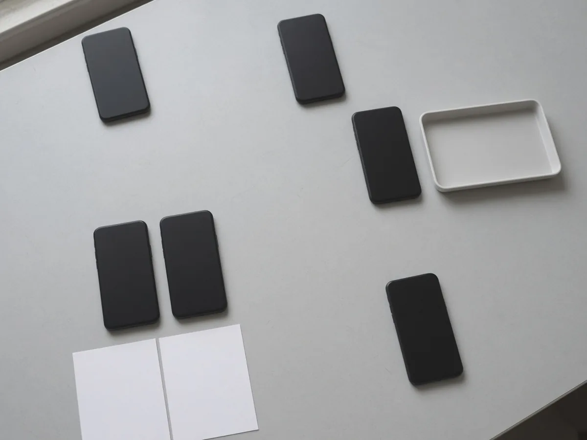 Four desk groups: two phones apart near a window, one phone beside an empty tray, two phones on blank sheets, and one phone alone.